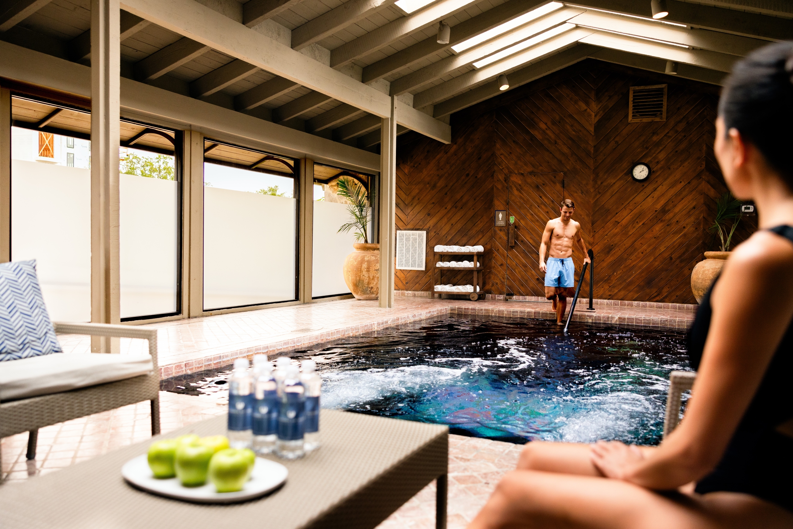 Woman watching a man getting into the indoor pool at the spa facility